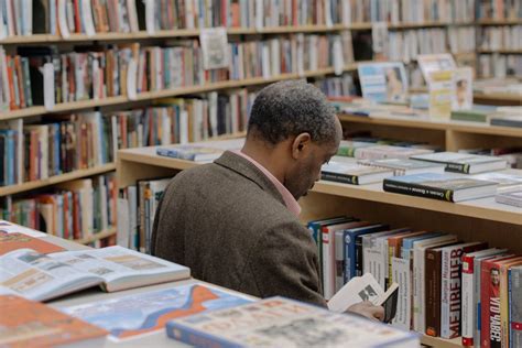 A Man Reading a Book on the Library · Free Stock Photo