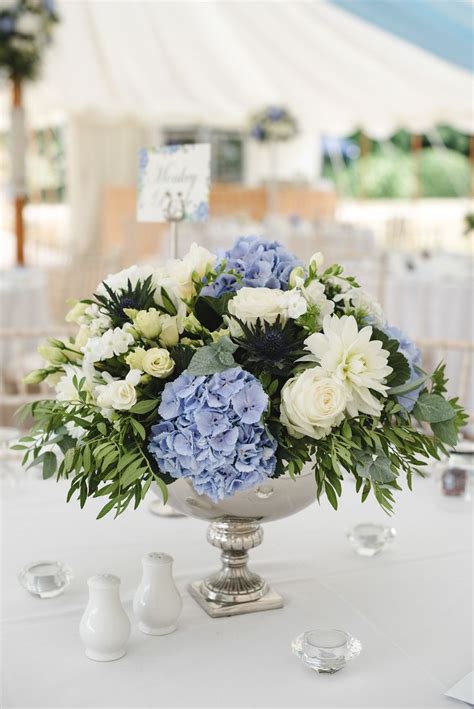 Silver footed bowls filled with ivory and blue flowers for a wedding ...