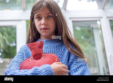 child holding a hot water bottle , trying to keep warm as fuel bills rocket Stock Photo - Alamy
