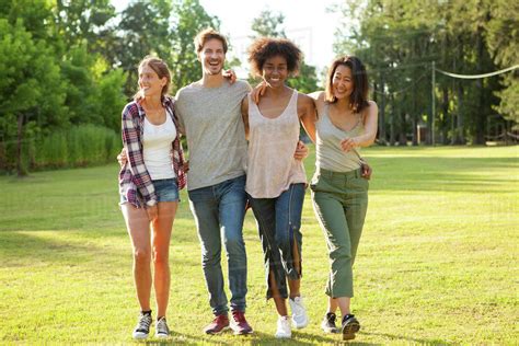 Happy young friends walking together in park - Stock Photo - Dissolve