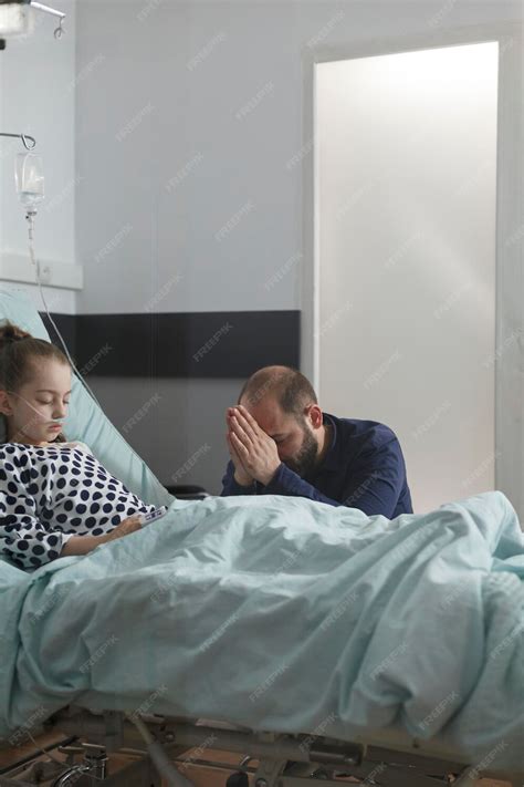 Free Photo | Worried father praying for sick daughter resting on patient bed. ill little girl ...