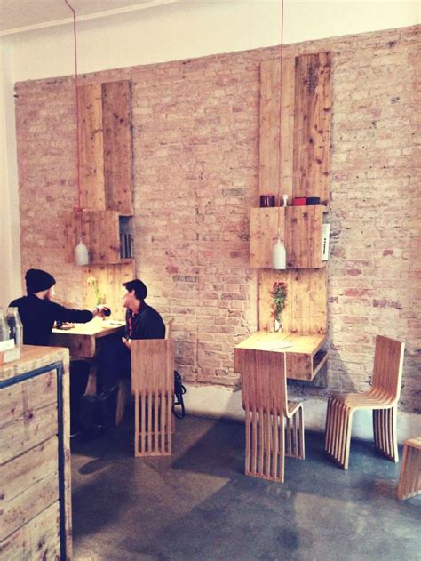 two people sitting at wooden tables in a brick walled room with exposed walls and flooring