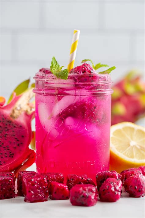 a pink drink in a mason jar surrounded by sliced lemons and raspberries