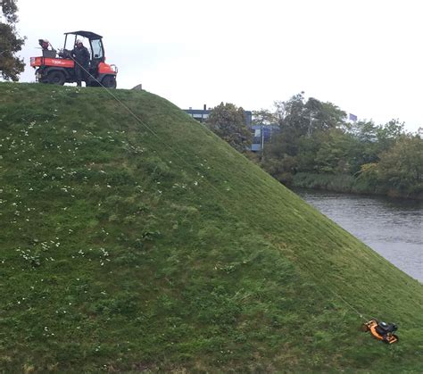 The grass on this steep hill is cut by lowering the mower and reeling it back up : r ...