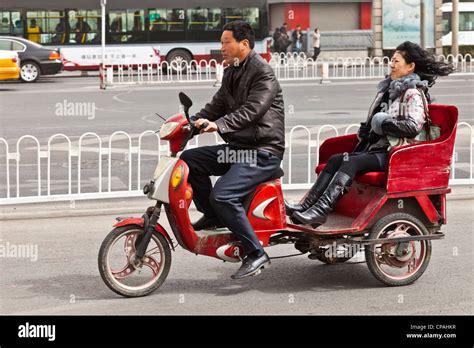 Woman being driven in an electric pedicab, Tiantan Dong Road, Beijing ...