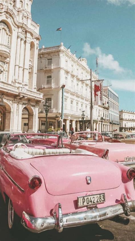 Download A Pink Car Parked In Front Of A Building Wallpaper | Wallpapers.com