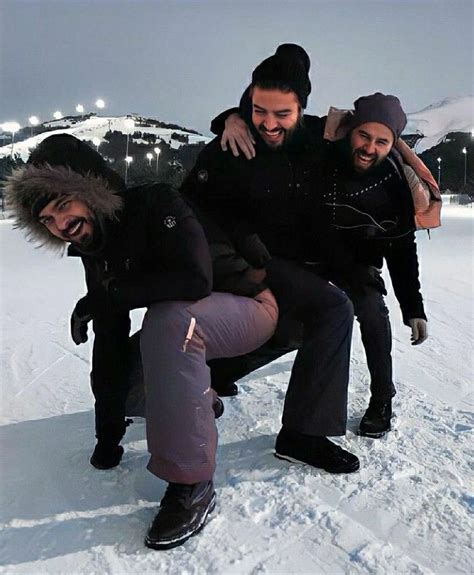 three people are sitting on a bench in the snow and one person is holding another man