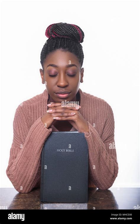 A young African American woman praying over the Holy Bible Stock Photo ...