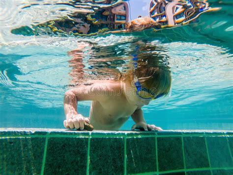 A Child Boy is Swimming Underwater in a Pool, Smiling and Holding ...