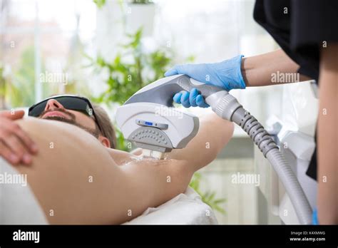 Men lying at beautician's during laser armpit hair removal therapy Stock Photo - Alamy