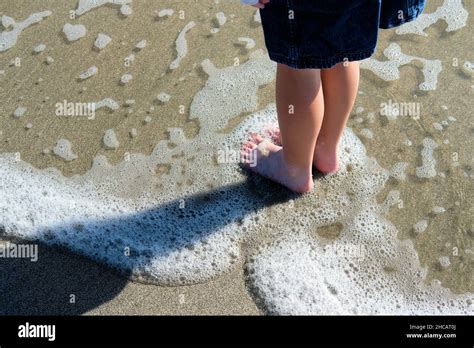 Feet and legs of a 10 year old little girl standing on the beach as ...