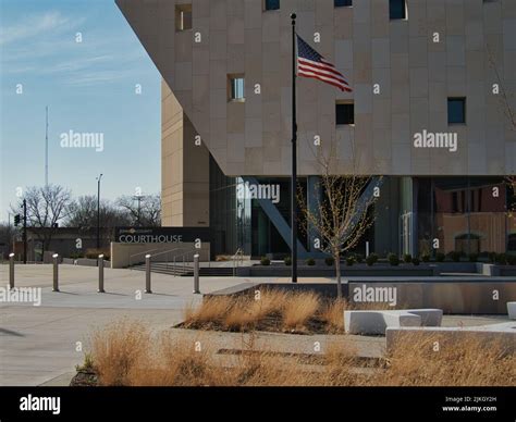 A view of a modern building of a Johnson County Courthouse and a waving flag in Olathe, Kansas ...