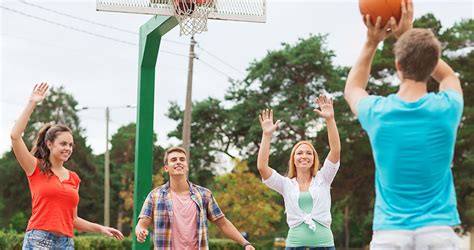 group of smiling teenagers playing basketball | Zoloox