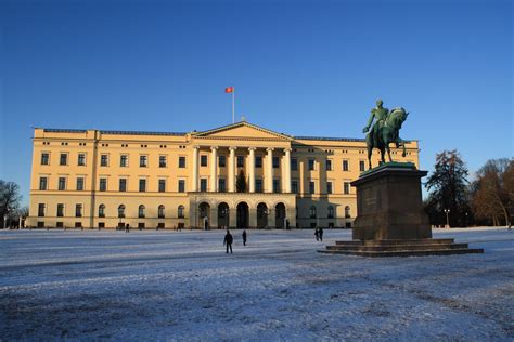 two people walking in front of a large building with a statue on the top of it