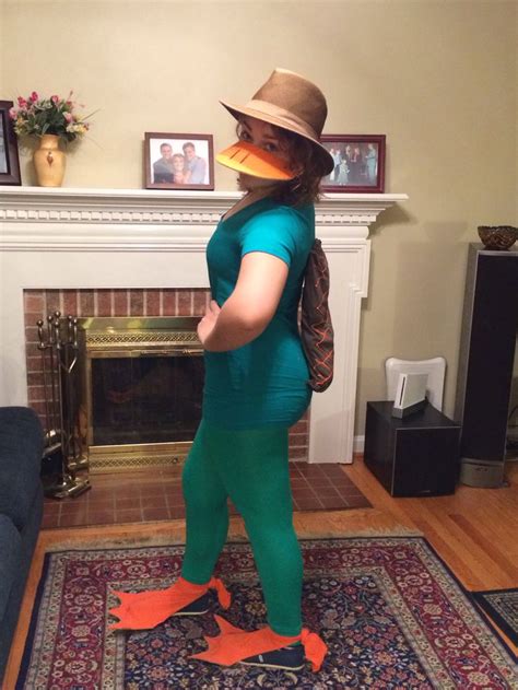 a woman in a green outfit and hat standing on a rug next to a fireplace