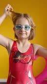 A Girl In A Red Swimsuit Puts On Swimming Glasses On A Yellow ...