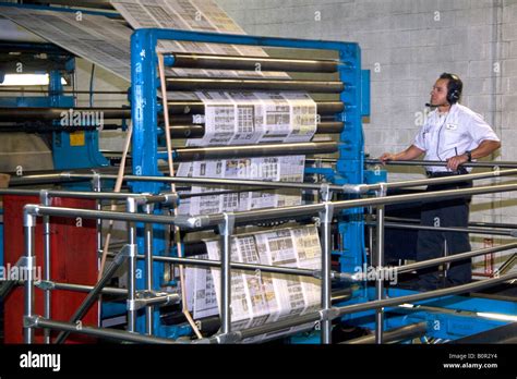 Pressman inspects newspapers being printed on a rotary printing press for the Houston Chronicle ...