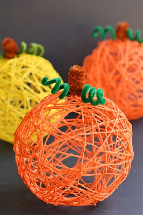 three orange and yellow yarn pumpkins sitting on top of a black surface with green stems