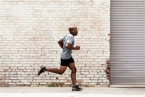 Black man running on city sidewalk - Stock Photo - Dissolve