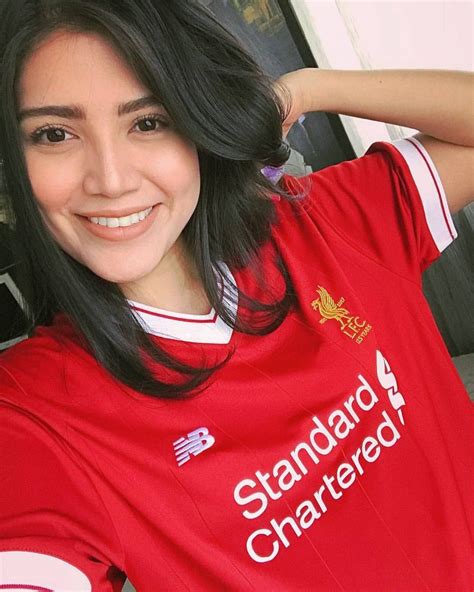 a woman with long black hair wearing a red shirt and smiling at the camera while standing in ...