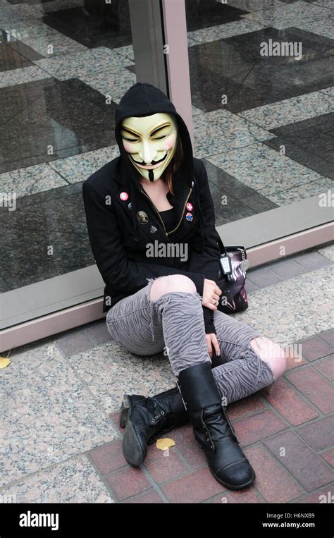 A female activist wearing a Guy Fawkes mask and a hoodie at a protest against the wall street ...