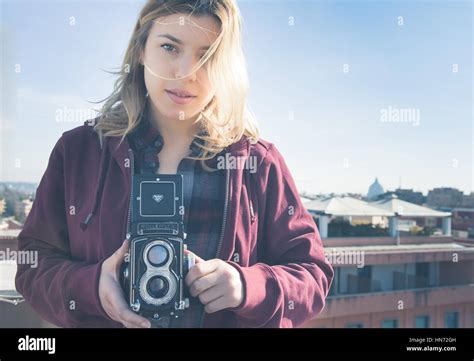 Young beautiful fascinating woman with old vintage Rolleflex camera and Rome city skyline in ...