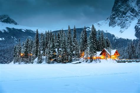 Premium Photo | Emerald lake with wooden lodge glowing in snowy pine ...