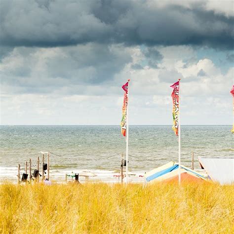 there are two boats on the beach with flags in the foreground and storm ...