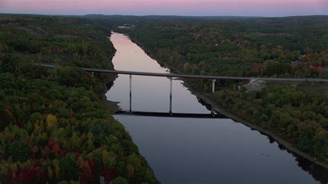 5.5K stock footage aerial video approaching small bridge spanning Kennebec River, autumn ...