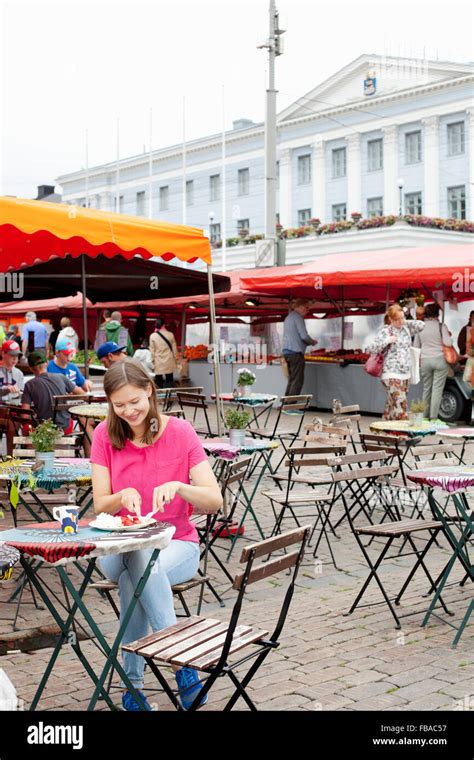 Finland, Uusimaa, Helsinki, Kauppatori, Young woman eating street food in open air restaurant ...