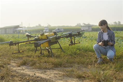 Young smart farmer controlling drone spraying fertilizer and pesticide over farmland,High ...