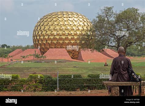 Auroville, India - March 16, 2018: An unidentified man looks out upon the Matrimandir temple in ...