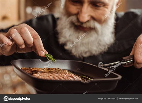 Man cooking steaks — Stock Photo © ArturVerkhovetskiy #139875844