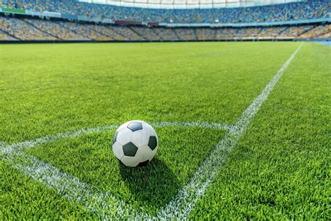 Soccer ball on grass in corner kick position on soccer field stadium - Stock Photo - Dissolve