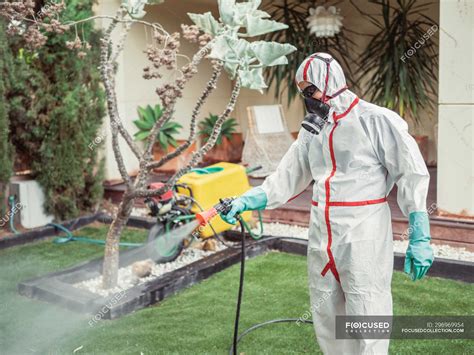 Fumigator in white uniform spraying substance on garden — fumigation ...