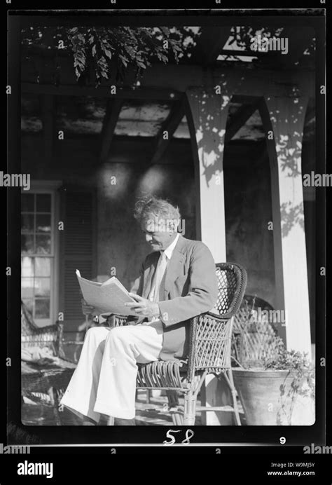 Arnold Genthe seated outdoors in a wicker chair reading Stock Photo - Alamy