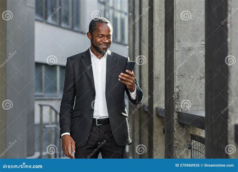 A Successful African American Businessman in a Business Suit is Standing on the Street Near a ...