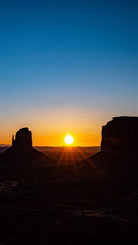 the sun is setting over monument buttes in arizona