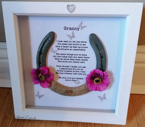 a white frame with pink flowers on it and a horseshoe hanging from the side, in front of a ...