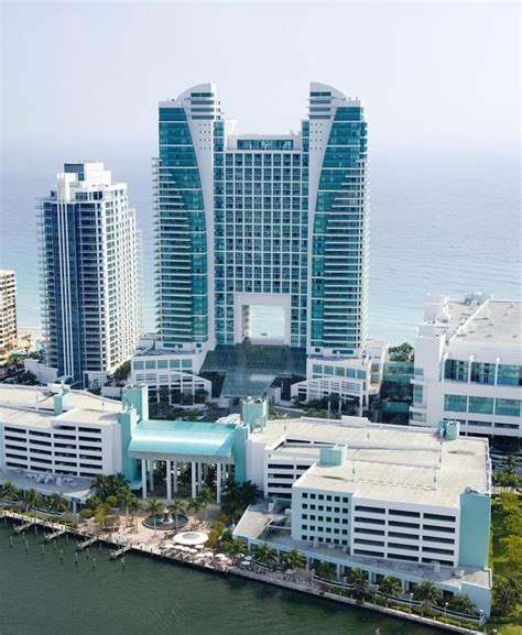 an aerial view of a city with tall buildings next to the water and trees in front of it