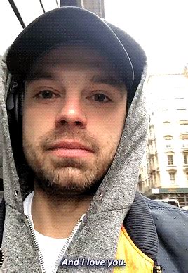 a man wearing headphones and a hoodie is standing in front of a building