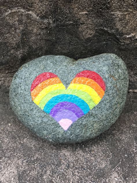 a rock with a rainbow painted on it in the shape of a heart and a rainbow