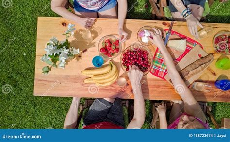 Family and Friends Eating Together Outdoors on Summer Garden Party. Aerial View of Table with ...