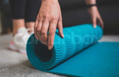 Woman rolling yoga mat. Home fitness training concept. | Stock image | Colourbox