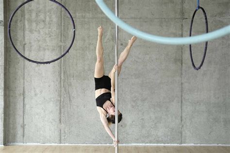 Woman practicing gymnastics on pole in front of concrete wall stock photo