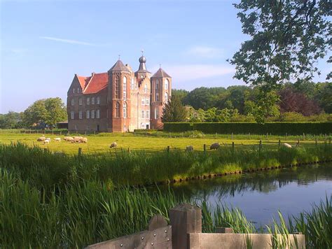 a large building sitting on the side of a lush green field next to a lake