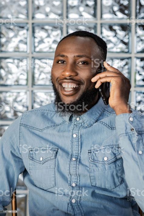 Smiling Black Man Having Phone Call Looking At Camera Against Glass Block Wall Stock Photo ...