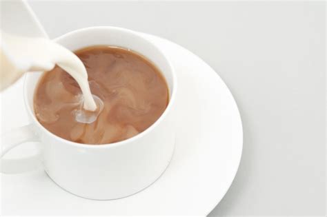 Pouring milk into a cup of coffee - Free Stock Image