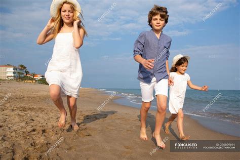 Happy and smiling children in casual wear running barefoot along ...