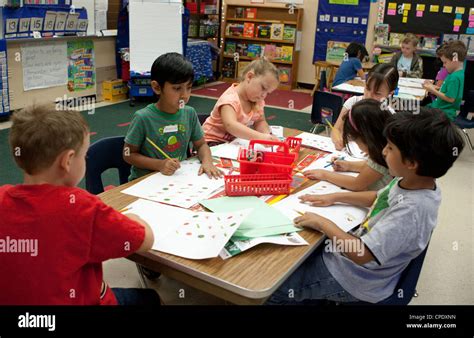 Multi-ethnic group of kindergarten students work at a large table in ...